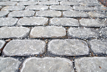 Paving slabs covered with rock salt used for winter deicing and road maintenance ensuring safety from icy and slippery urban surfaces. Rock salt spread, winter deicer, selective focus