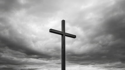A solitary cross stands against a dramatic, cloudy sky, evoking themes of faith. Black and white image captures wooden cross silhouetted against backdrop of ominous, swirling clouds, symbolizing hope