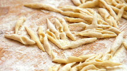 Strozzapreti pasta fresh raw dough on wooden board