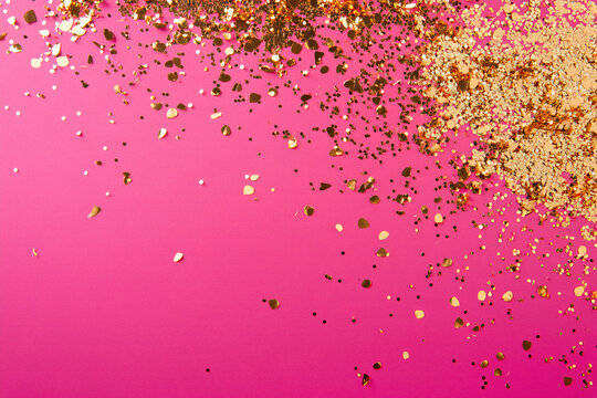 Golden confetti on a pink background.
