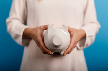 A woman holding a white piggy bank, symbolizing savings, finance, and financial security. Ideal for...