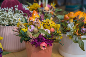 decorative autumn dried flower arrangement in a pink bucket with yellow orchids, purple hydrangeas, baby's breath, and whimsical ceramic mushrooms, concept of thanksgiving, halloween, or fall decor
