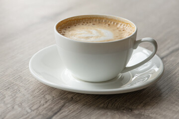 Cup of hot cappuccino coffee on table