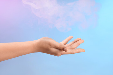 Female hand with energy smoke on blue background
