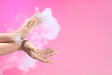 Female hands with energy smoke on pink background