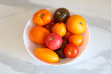 Assorted heirloom tomatoes in bowl on marble surface