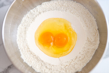 Flour mixture with two egg yolks in bowl for baking preparation