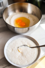 Baking preparation with eggs in bowl and foamy mixture on spoon