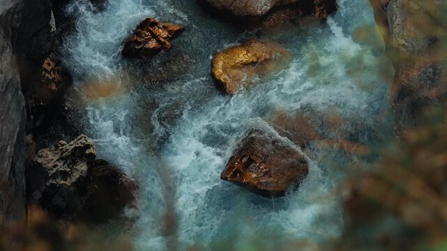 Energetic footage of clear alpine water rushing over rocks, showing the power and movement of a mountain river surrounded by raw wilderness and rugged terrain.