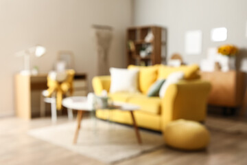 Blurred view of stylish living room with yellow sofa and artificial houseplant on coffee table