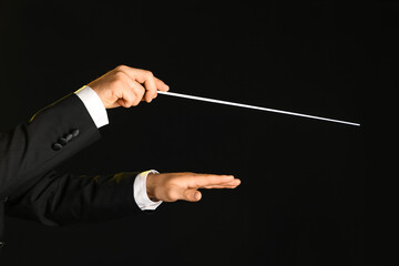 Hands of male conductor with baton on black background