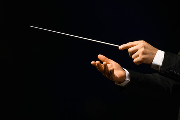 Hands of male conductor with baton on black background