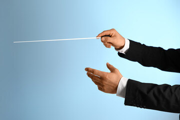 Hands of male conductor with baton on blue background