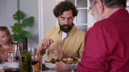 Three generations of men sharing food at family dinner