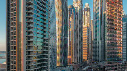 Obraz premium View of modern skyscrapers shining in sunset lights timelapse in Dubai Marina in Dubai, UAE.