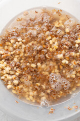 Overhead view of beans being washed, top view of honey beans being washed to make nigerian moi-moi or bean cake, process of peeling beans skin by hand
