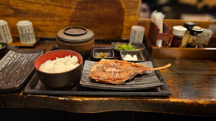 Japanese grilled fish set meal with fresh salmon and sea bream served on a wooden table, with steamed rice, side dishes, and hot miso soup in a local restaurant