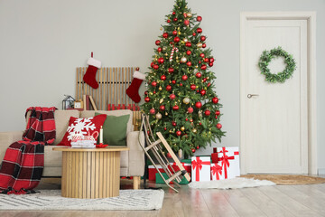 Interior of festive living room with white sofa, sled, gifts and Christmas tree
