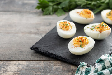 Homemade hard Boiled Deviled Eggs garnished with herbs on wooden table. Copy space