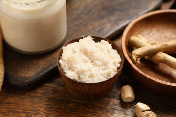 Bowl with horseradish sauce on wooden boards as background, closeup