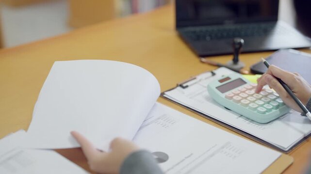 Close-up of woman reviewing financial charts and budget documents with calculator. Accounting and finance work concept.
