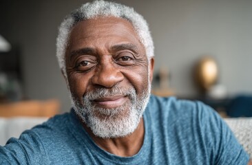 Close-up of a smiling elderly man with gray hair and beard wearing a blue shirt