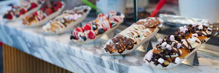Sweet pancakes with toppings sold as street food. Banner with blurred copy space.
