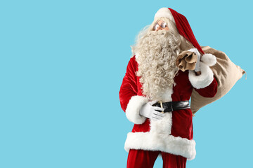 Santa Claus with bag full of gifts on blue background