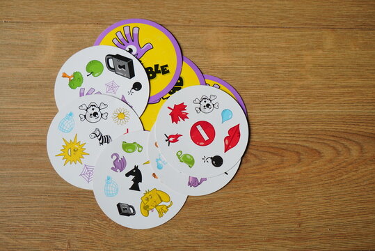 The popular card game 'Dobble', also known as 'Spot It!', with its distinctive round cards featuring various symbols, laid out on a wooden table