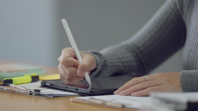 University student writing notes on digital tablet with stylus pen. Productivity, digital note-taking, and education tools.