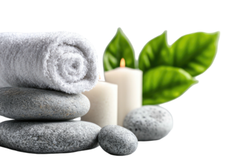 Peaceful spa setup, featuring a stack of smooth stones, rolled towel, lit candles and greenery