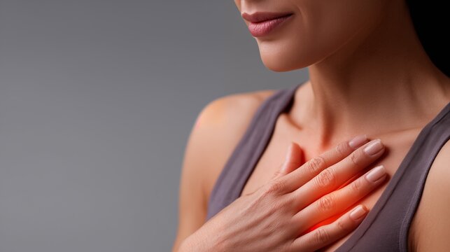 Young woman feeling heartburn pressing hand to chest, close up studio portrait on gray background