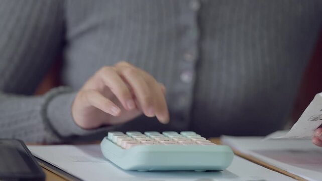 Focused student reviewing notes and calculating figures using calculator. Preparation for accounting exam or finance project.
