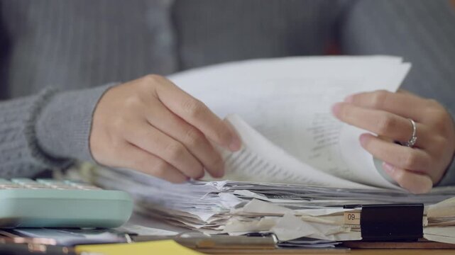Close up of Asian woman s hands organizing stack of papers symbolizing office work, administration, accounting, or document management
