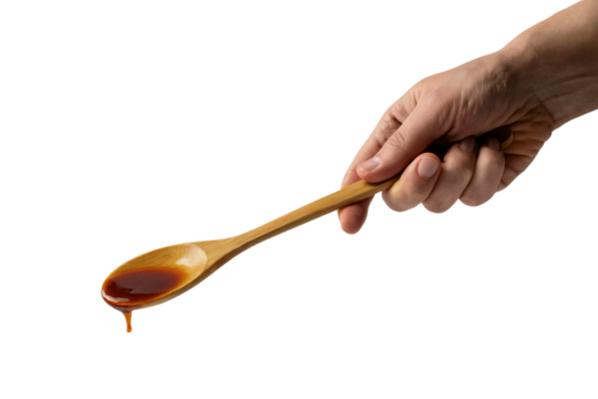 A hand holding a wooden spoon with sauce dripping off. Isolated on transparent background, png