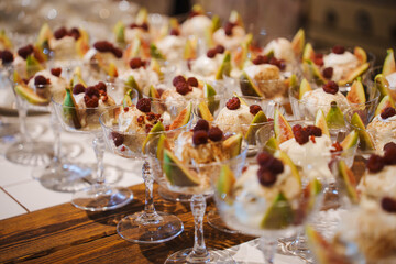 Desserts arranged in elegant glasses with fruits at a celebration event