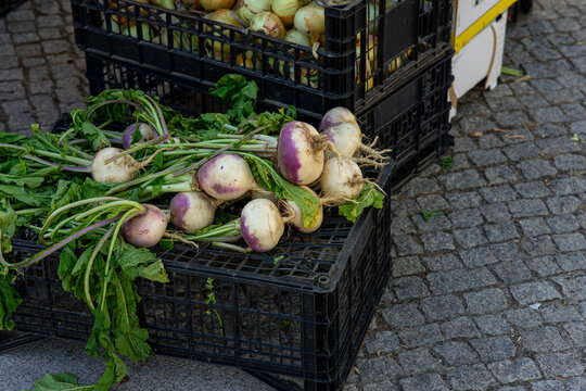 Fresh turnips with leafy greens displayed at a small farmers' market stall, showcasing locally grown root vegetables for healthy cooking and seasonal meals.