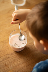 Child stirring chia seeds in pink coconut milk glass