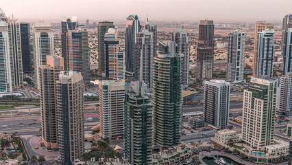 Obraz premium Dubai Marina skyscrapers and jumeirah lake towers view from the top aerial night to day timelapse in the United Arab Emirates.
