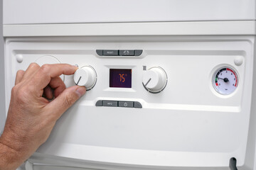 Adjusting thermostat setting on home heating system central heating boiler