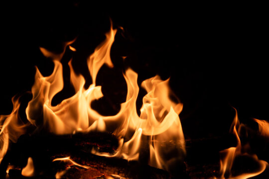 Flammes d'un feu de chemin&eacute;e en premier plan, arri&egrave;re plan noir