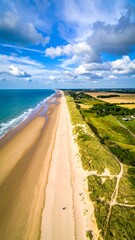 Coastal panorama, aerial view of a wide, sandy beach stretching towards the horizon.  Pale sand meets turquoise ocean water, interspersed with dunes and vegetation.  A clear sky with scattered clouds