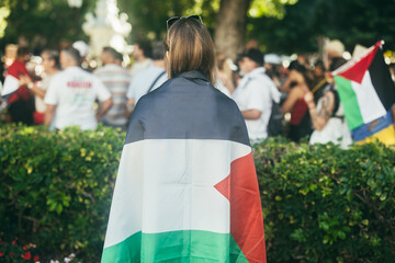 Young caucasian woman protest at demonstration wearing Palestine flag - Solidarity and march against genocide concept - Focus on head