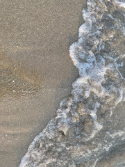 Gentle ocean waves lapping against sandy shore in soft light during a peaceful afternoon