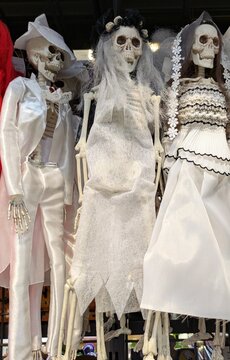 Grupo de esqueletos de pl&aacute;stico con ropa de hombre y mujer para decoraci&oacute;n de Halloween en estante de comercio