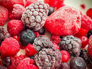 Assorted frozen berries including strawberries, raspberries, blackberries, and blueberries on a white surface