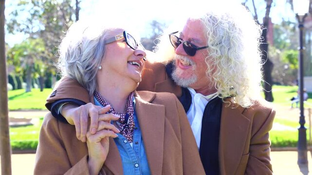 Joyful elderly couple smiling and embracing outdoors in sunny park, expressing love, happiness, and togetherness during a beautiful day, concept of aging well, senior lifestyle, retirement joy