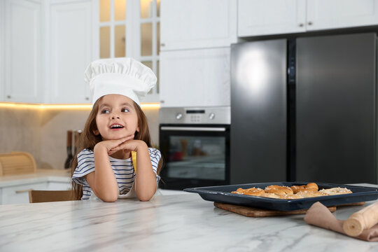 Choice of profession. Little girl with pastries pretending to be chef in kitchen