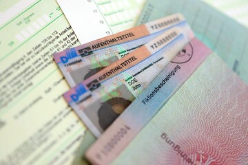 German Permanent resident card and temporary document lies on tax form. Aufenthaltstitel
