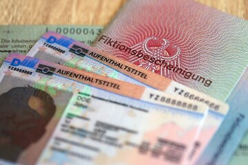 German Permanent resident card and document specimen lies on wooden table. Aufenthaltstitel